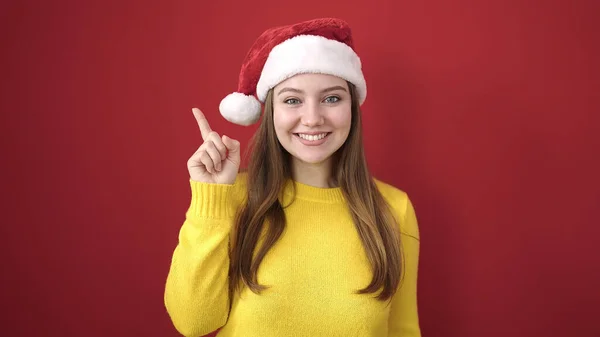 単離された赤い背景上のアイデアのジェスチャーでクリスマスの帽子をかぶっている若い金髪の女性 — ストック写真