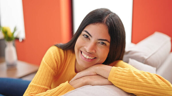 Young beautiful hispanic woman smiling confident sitting on sofa at home