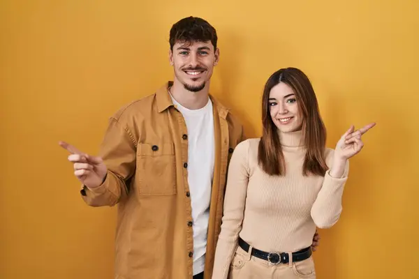 Young Hispanic Couple Standing Yellow Background Smiling Confident Pointing Fingers — Stock Photo, Image