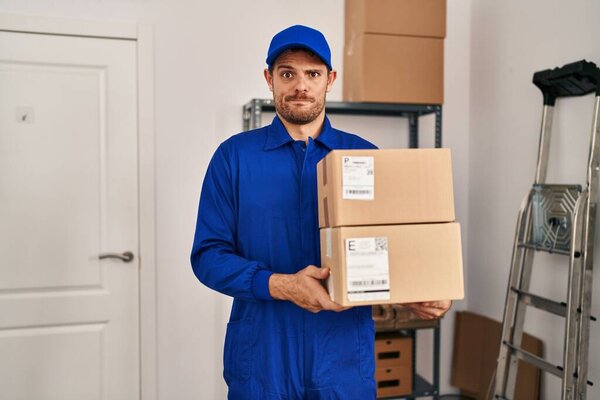 Young hispanic man working on moving service holding boxes skeptic and nervous, frowning upset because of problem. negative person. 