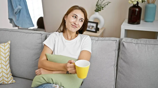 ソファーに座ってコーヒーを飲む若い女性が自宅で考える — ストック写真