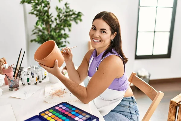 若い美しいですヒスパニック女性アーティスト笑顔自信に満ちた絵画粘土鍋でアートスタジオ — ストック写真