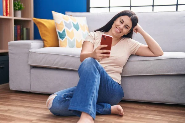年轻美丽的惊慌失措的女人坐在家里的地板上用智能手机 — 图库照片
