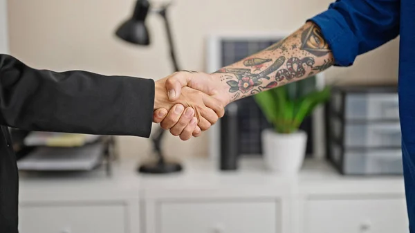 Two business workers shake hands at the office