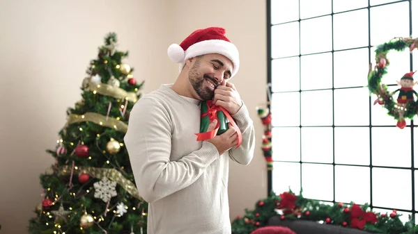 Young Hispanic Man Hugging Gift Standing Christmas Tree Home — Stock Photo, Image