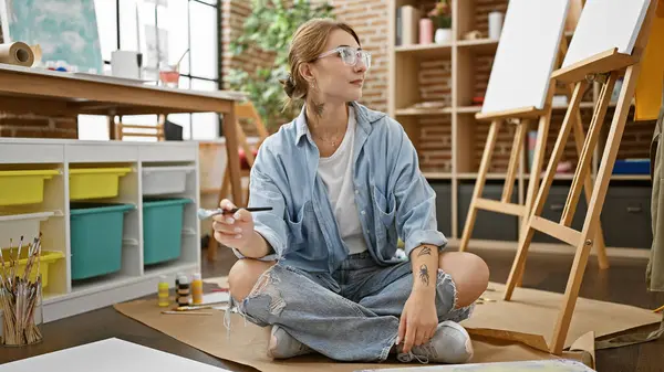 Resim Stüdyosunda Elinde Fırçayla Oturan Genç Bir Kadın Sanatçı — Stok fotoğraf