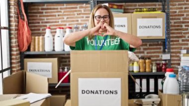 Orta yaşlı İspanyol kadın gönüllü gülümsüyor. Yardım merkezinde kalp hareketi yapıyor.