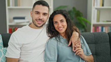 Erkek ve kadın çift evdeki kanepede oturup birbirlerine sarılıyorlar.