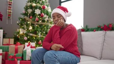 Afrikalı Amerikalı kadın evde üzgün bir ifadeyle Noel 'i kutluyor.