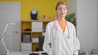 Klinikte kendine gülen genç sarışın kadın doktor.