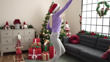 Genç sarışın kadın Noel ağacının yanında duruyor evde dans ediyor