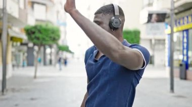 Sokak ortasında müzik dinleyen ve dans eden Afrikalı Amerikalı bir adam.