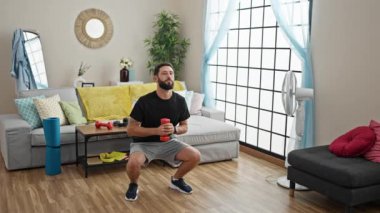 Dambıl kullanan genç bir İspanyol evde bacak egzersizi yapıyor.