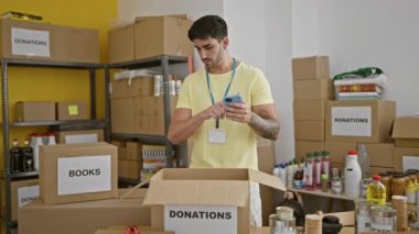 Genç İspanyol gönüllü yardım merkezinde akıllı telefon kullanarak ürünleri kontrol ediyor.