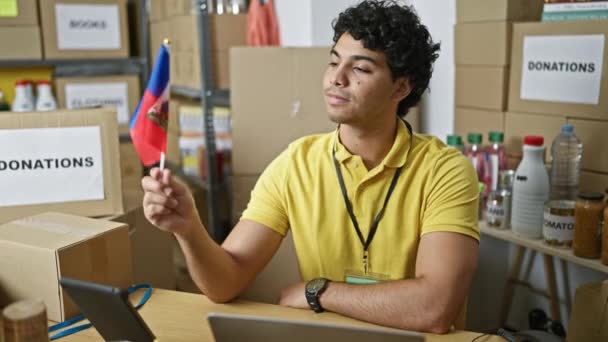 Joven Voluntario Latino Sosteniendo Bandera Haiti Sonriendo Centro Caridad — Vídeos de Stock