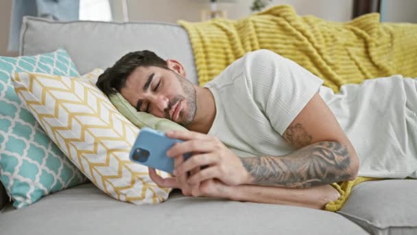 Young Hispanic Man Lying Sofa Tired Using Smartphone Home — Stock Video