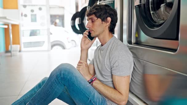 Young Hispanic Man Talking Smartphone Waiting Washing Machine Laundry Facility — Stock Video