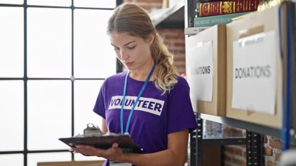 Νεαρή Ξανθιά Εθελόντρια Γράφει Στο Πρόχειρο Ελέγχοντας Στο Φιλανθρωπικό Κέντρο — Αρχείο Βίντεο