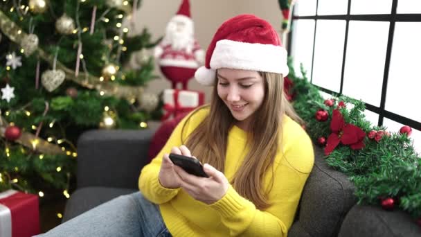 Junge Blonde Frau Sitzt Mit Smartphone Hause Auf Sofa Weihnachtsbaum — Stockvideo