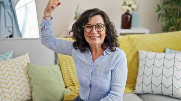 中年惊慌失措的女人充满自信地微笑着 在家里用胳膊做着强有力的手势 — 图库视频影像