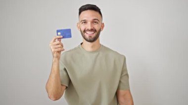 Genç İspanyol adam gülümsüyor. Kredi kartı ve dolarları soyutlanmış beyaz arka planda tutuyor.