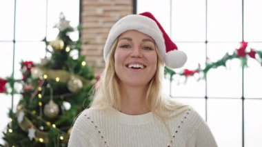 Genç sarışın kadın gülümseyerek Noel 'i evde kutluyor.