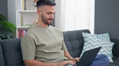 Genç İspanyol adam bilgisayarını kapatıp evde gülümsüyor.
