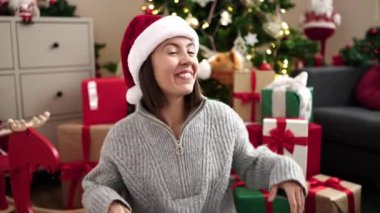 Evdeki Noel ağacının yanında kendinden emin gülümseyen güzel İspanyol kadın.