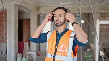 Şantiyedeki kulaklıkları çıkarırken ses çıkaran çapraz kollu İspanyol bir müteahhit.