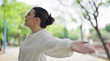 Parkta kollarını açmış genç ve güzel bir İspanyol kadın.