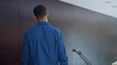 Genç İspanyol iş adamı. Ofiste kollarını kavuşturup el kol hareketi yapıyor.