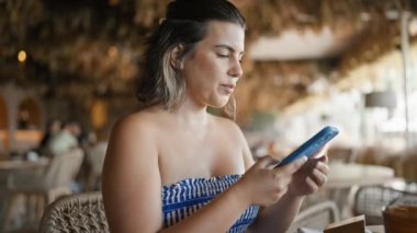 Genç İspanyol kadın restoranda yemek menüsünü görmek için QR kodunu tarıyor.