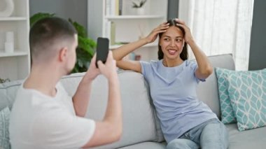 Güzel bir çift, evlerindeki koltuklarında birlikte oturup eğlenceli, sıradan bir cep telefonu fotoğrafı çekmenin tadını çıkarıyorlar. Aşk, gülümseme ve güzel bir ilişki anında yakalanan kapalı bir yaşam tarzı..