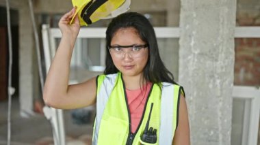 Genç Çinli mimar gülümsüyor. İnşaat alanında şapkasını çıkarıyor.