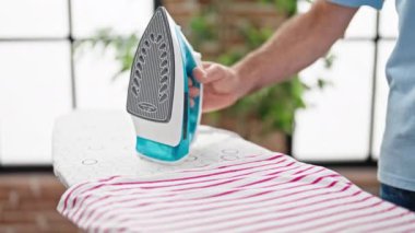 Middle age man ironing clothes at laundry room
