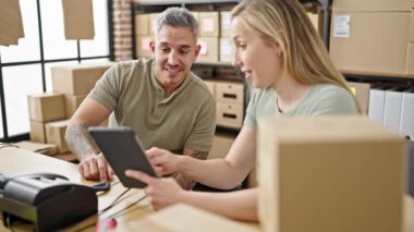 Erkek ve kadın ekomünikasyon işçileri dokunmatik ped kullanıyorlar ve ofiste birbirlerine sarılıyorlar.