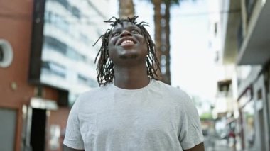 Afro-Amerikalı adam gülümsüyor. Gökyüzüne bakıyor ve kutluyor.