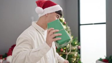 Genç İspanyol adam elinde Noel hediyesi tutarak evde dans ediyor.