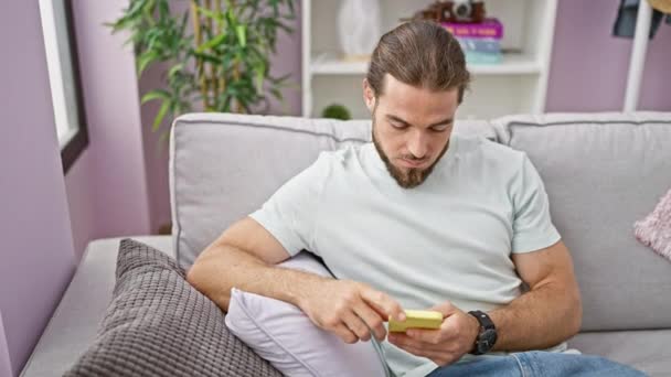 Hombre Hispano Joven Usando Teléfono Inteligente Sentado Sofá Mirando Molesto — Vídeos de Stock