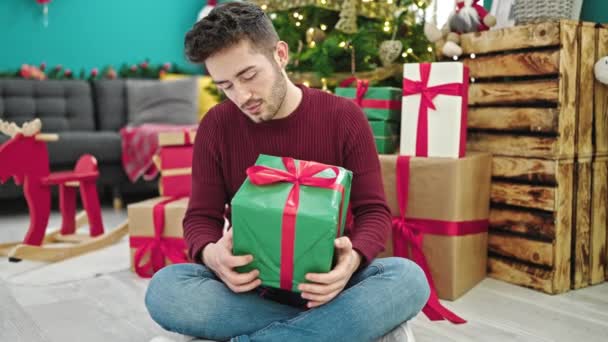 Молодий Іспаномовний Чоловік Тримає Різдвяний Подарунок Посміхається Вдома — стокове відео