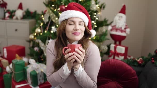 Ung Smuk Spansktalende Kvinde Drikker Kaffe Sidder Sofaen Ved Juletræ – Stock-video