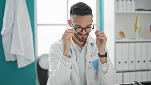 Kollarını Kavuşturup Masada Oturan Genç Spanyol Doktor Klinikte Gözlüklerini Çıkartıyor — Stok video