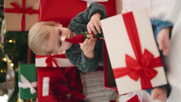 可爱的金发碧眼的幼儿抱着圣诞礼物的精灵玩具坐在家里的地板上 — 图库视频影像