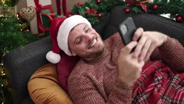 Jeune Homme Caucasien Utilisant Smartphone Couché Sur Canapé Par Arbre — Video