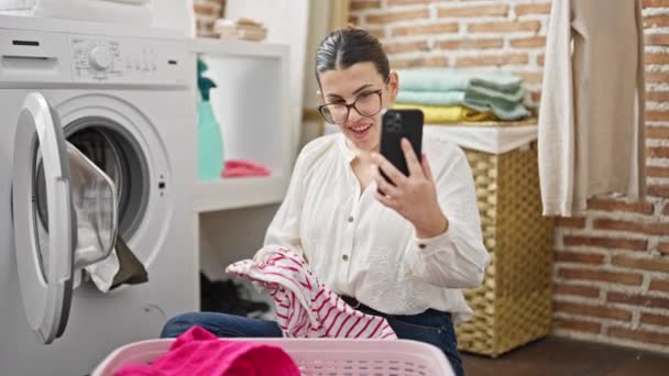 年轻美丽的惊慌失措的女人在洗衣房用智能手机洗衣服 — 图库视频影像