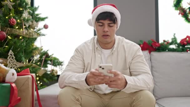 Jeune Homme Hispanique Utilisant Smartphone Célébrant Noël Malheureux Maison — Video