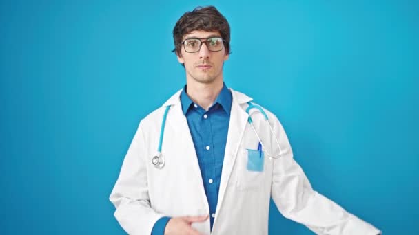 若いですヒスパニック男医師作る誓いとともに手上の胸上の隔離された青の背景 — ストック動画