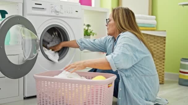 中年恐慌的女人坐在洗衣房的地板上洗衣服 — 图库视频影像