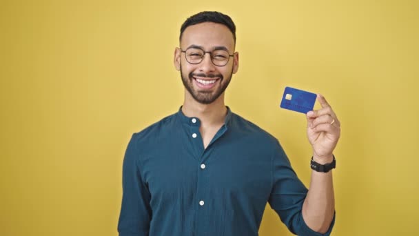 Joven Hombre Hispano Sonriendo Confiado Sosteniendo Tarjeta Crédito Sobre Fondo — Vídeos de Stock