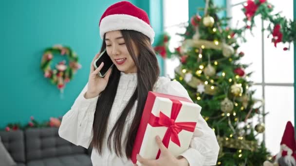 中国的年轻女性正拿着圣诞礼物在家里用智能手机交谈 — 图库视频影像